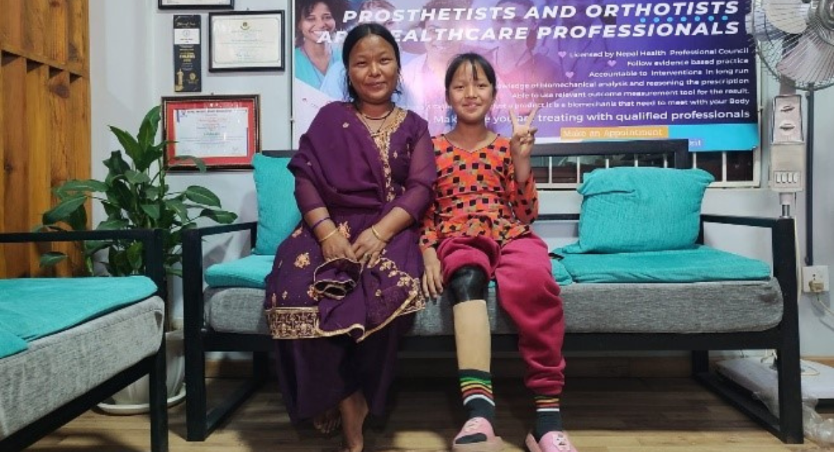 Man Kumari and her mother sitting on a couch smiling. Cover Image
