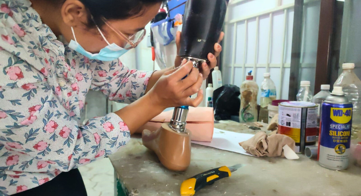 A technician repairing the bottom of a prosthetic limb. Cover Image