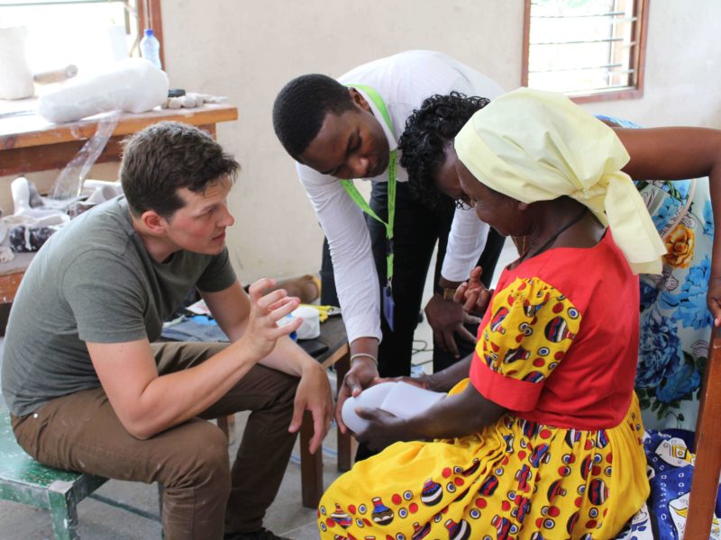 A team of technicians helping to fit a prosthetic device on a kenyan woman's leg Cover Image