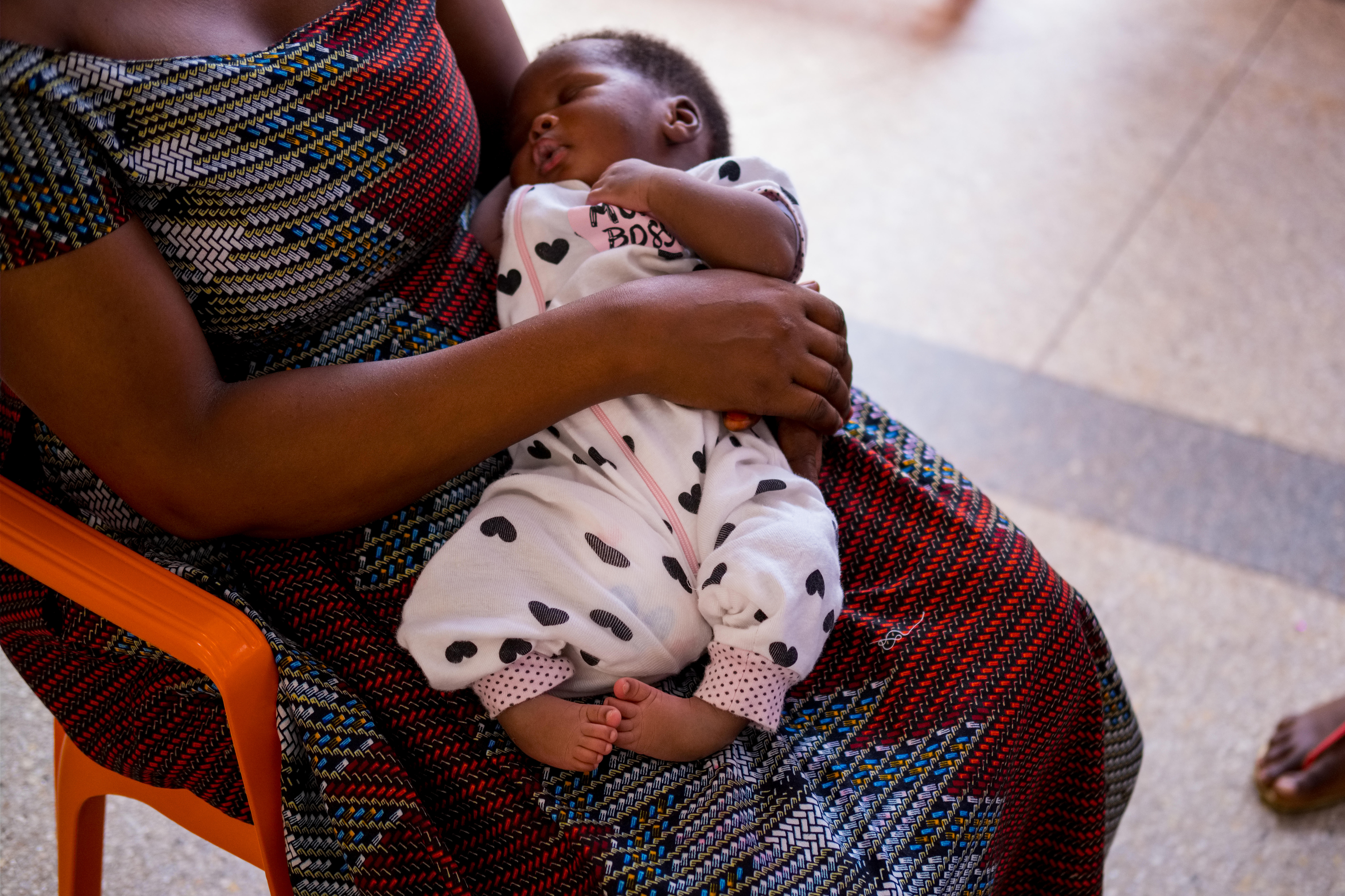 A woman sitting on a chair with an infant with clubfoot condition