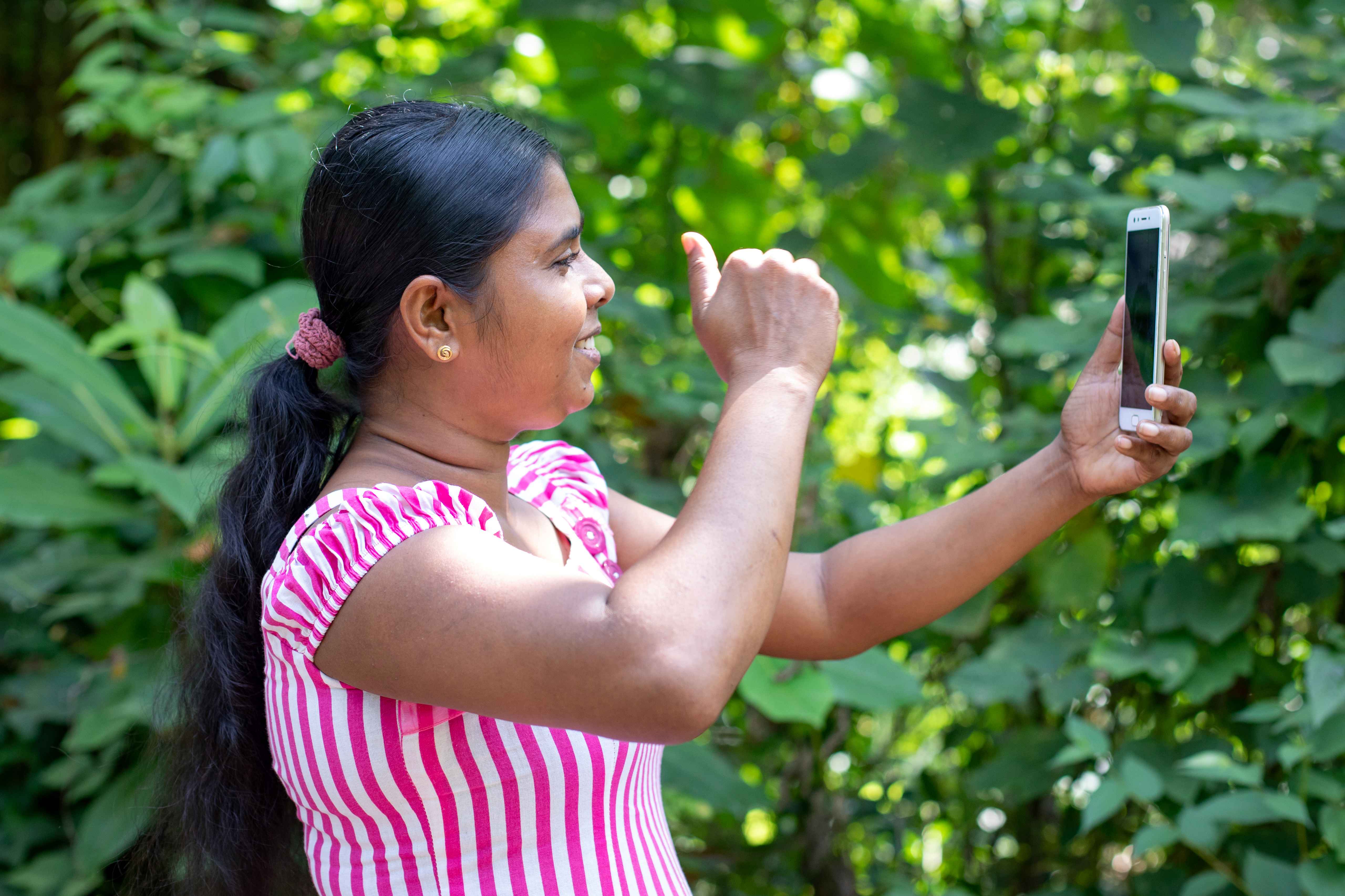 Women in Sri Lanka engaging with mobile outdoor, shielding eyes from the sun